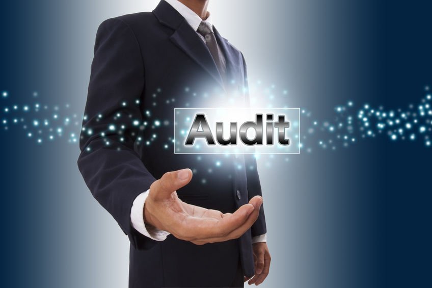 The word Audit highlighted in a businessman's hand